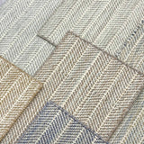 Close up of broadloom carpets with striated herringbone weave in a range of cool neutral colors. 