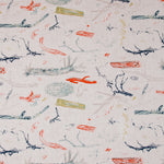 Detail of fabric in a painterly tree branch print in shades of blue, navy and red on a greige field.