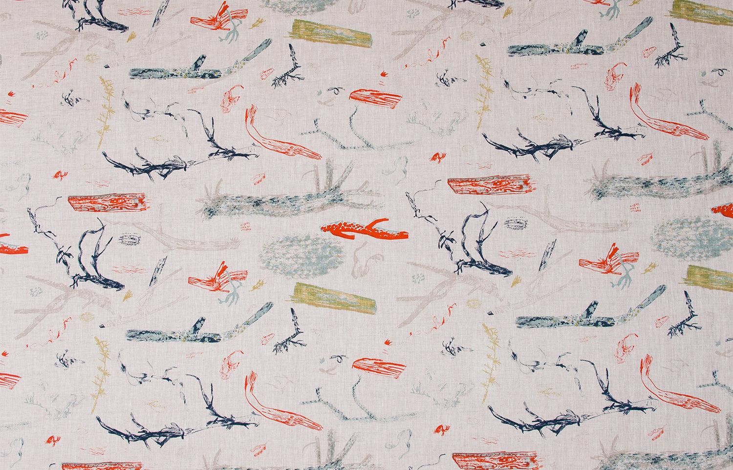 Detail of fabric in a painterly tree branch print in shades of blue, navy and red on a greige field.