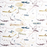 Detail of fabric in a painterly tree branch print in shades of brown, yellow and blue on a white field.