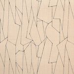 Detail of fabric in an abstract lattice print in black on a tan field.