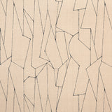 Detail of fabric in an abstract lattice print in black on a tan field.