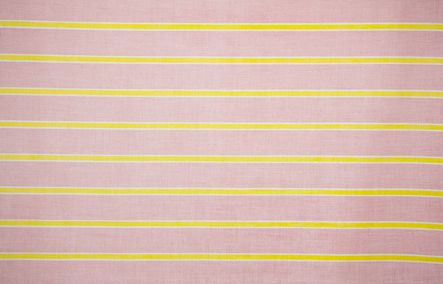 Detail of fabric in a horizontal striped print in yellow and white on a pink field.