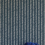 A vase of flowers stands in front of a wall covered in a repeating striped circular print in cream on a navy field.