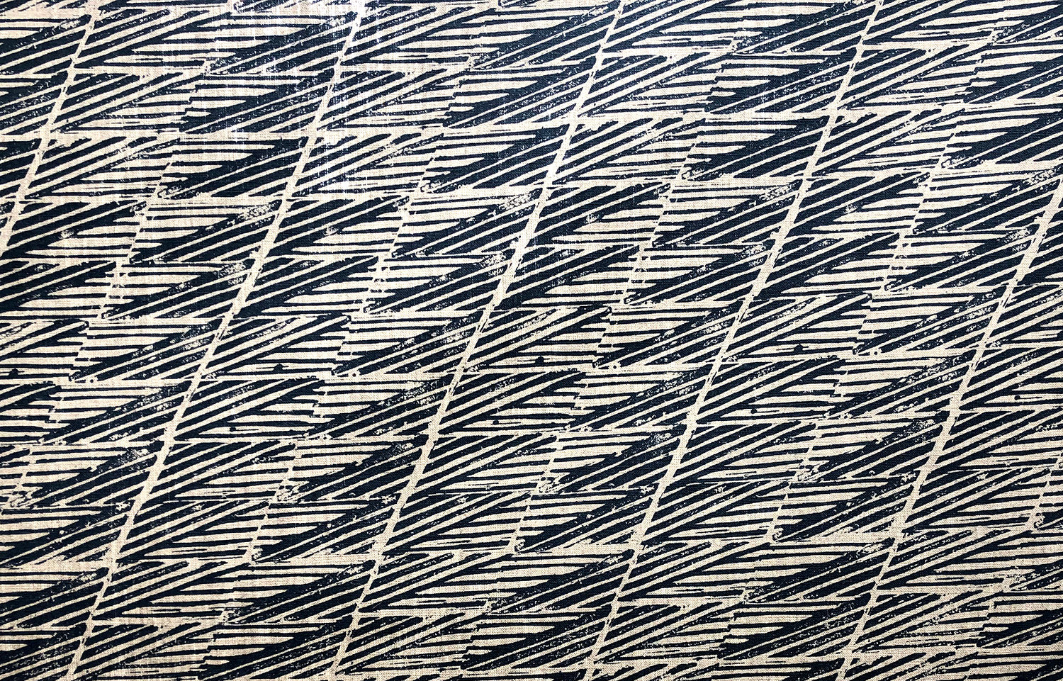 Detail of fabric in a textural geometric stripe in navy on a tan field.