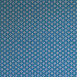 Detail of wallpaper in a minimalist quatrefoil pattern in light pink on a blue field.