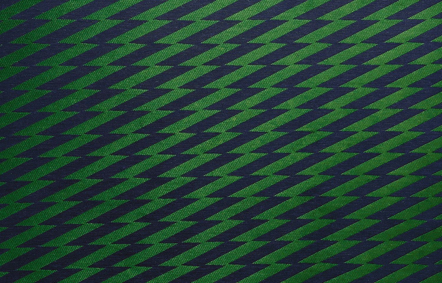 Detail of fabric in a zigzag stripe print in navy on a green field.