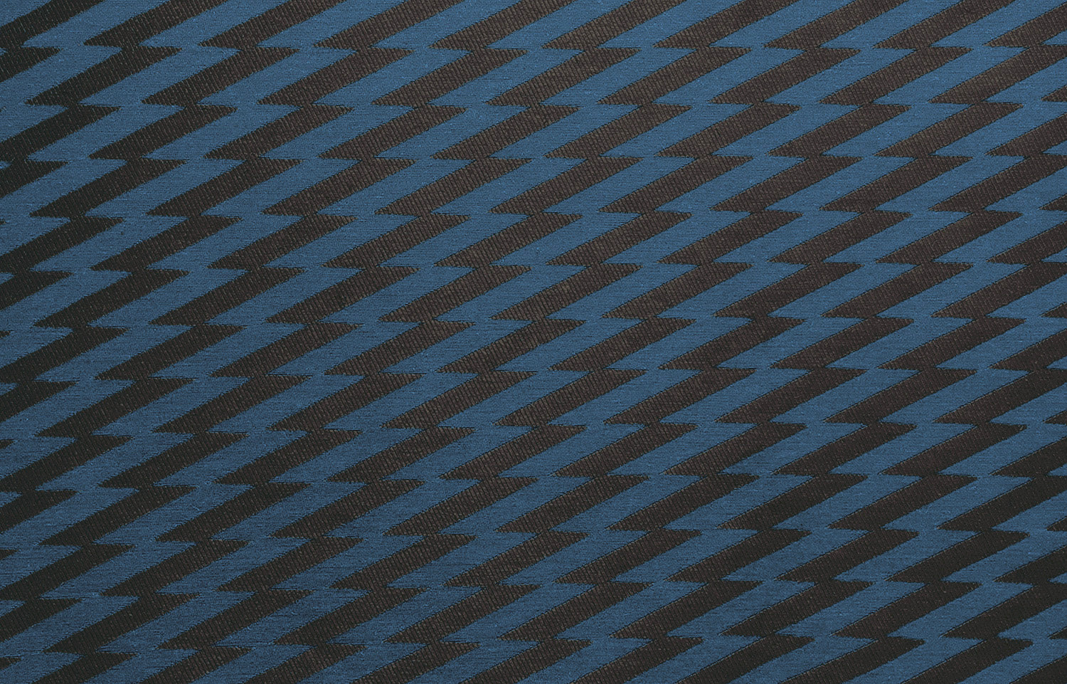 Detail of fabric in a zigzag stripe print in navy on a black field.