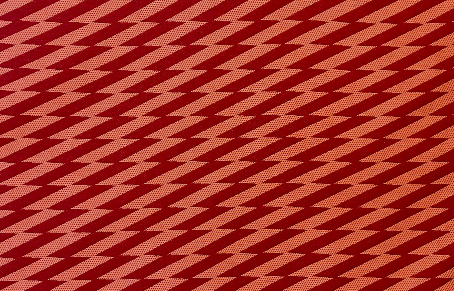 Detail of fabric in a zigzag stripe print in red on a burnt orange field.