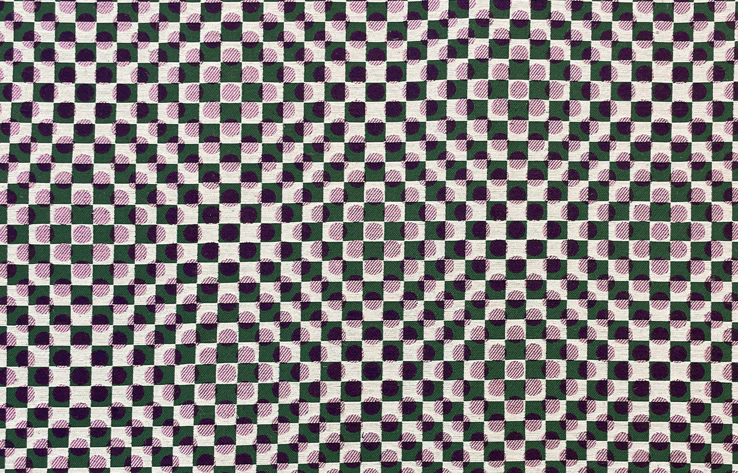 Detail of fabric in a geometric check and polka dot pattern in pink, black, cream and green.