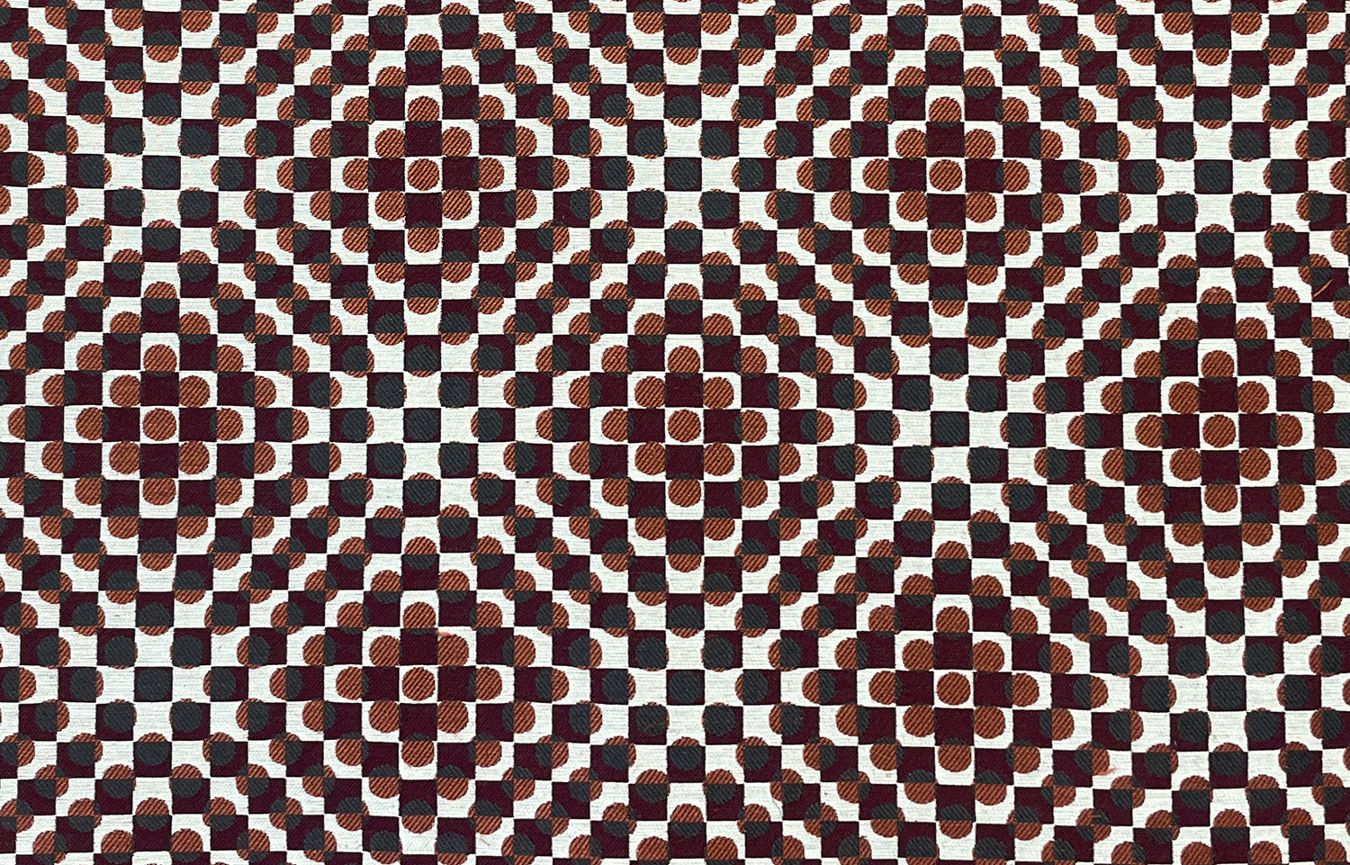 Detail of fabric in a geometric check and polka dot pattern in burnt orange, green, cream and black.