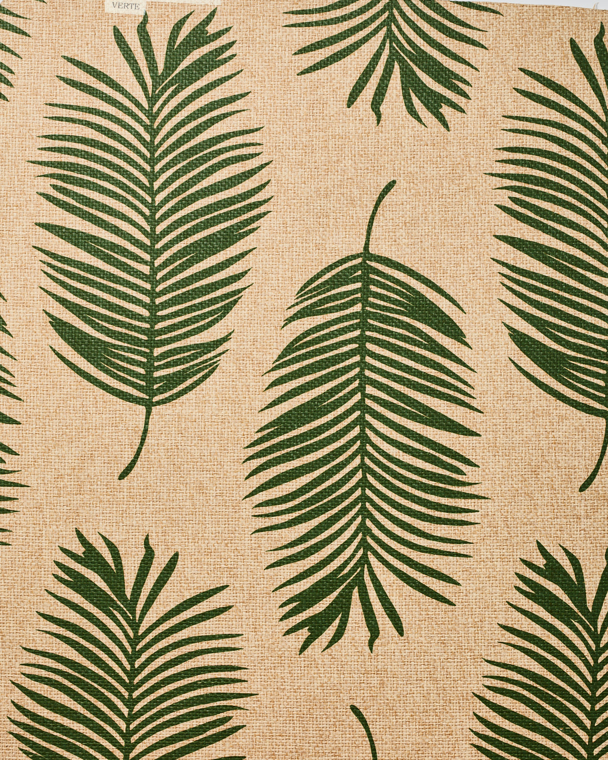 Detail of fabric in a large-scale leaf print in dark green on a tan field.