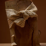 Wooden log with a checkered cloth tied around it against a brown background