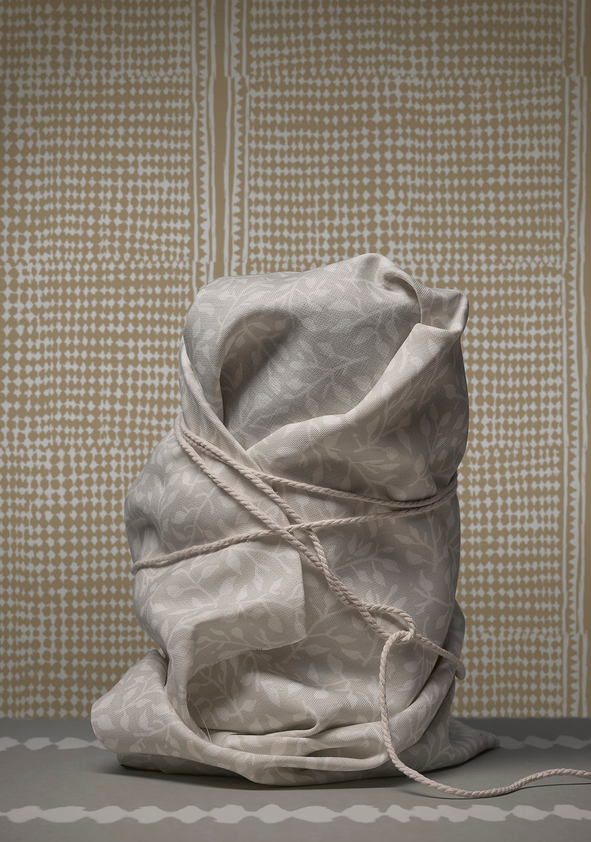 Tied sack made of fabric against a textured wall.