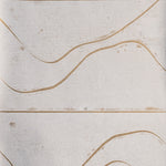 Detail of wallpaper in an abstract linear print in tan on a mottled cream field.