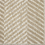 Close up of a woven herringbone design carpet in beige.