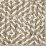 Close-up of a textured beige and white woven diamond pattern rug. 