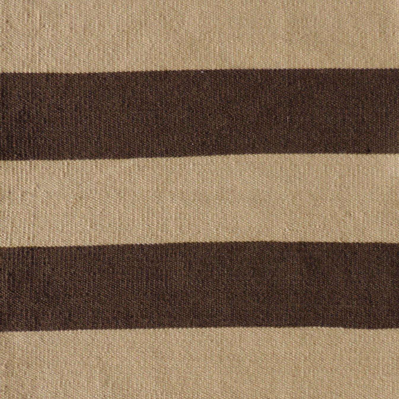 Handwoven rug with wide stripes in tan and dark brown. 