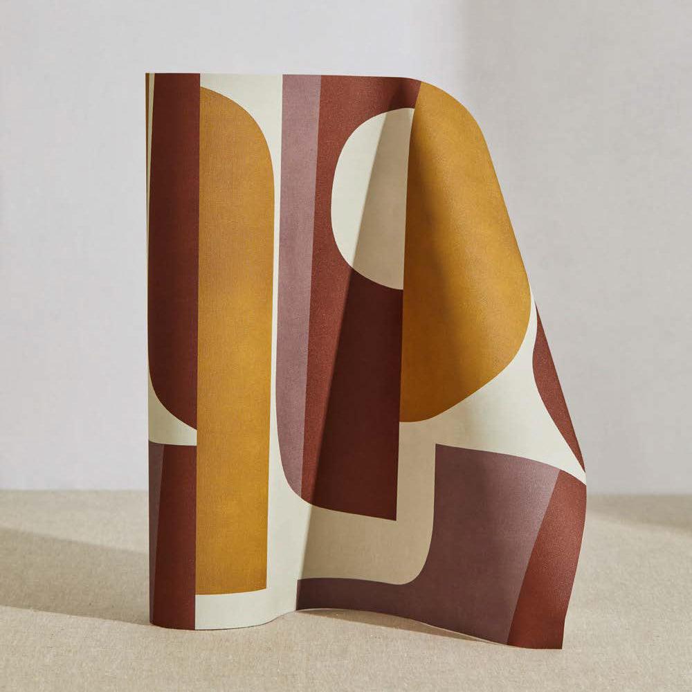 A curved partition stands on the ground, covered in a curvilinear geometric grid print in shades of mustard, purple, and cream.