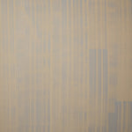 A table with a vase of buds stands in front of a wall papered in mottled gray and blue stripes.