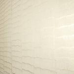 Wide-angle shot of wallpaper in an abstract textural pattern in cream and metallic.