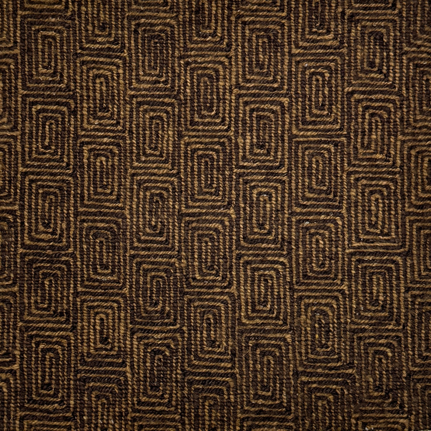 A close-up of flatweave rug  with a repeating geometric pattern in dark brown and tan. 