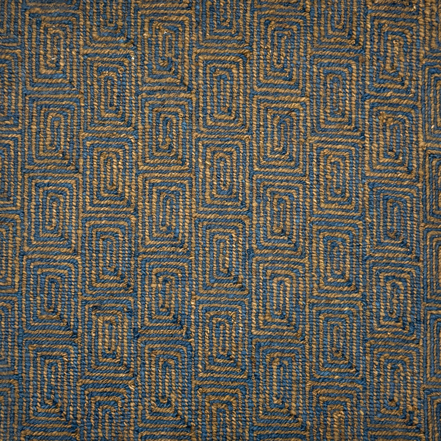 A close-up of flatweave rug  with a repeating geometric pattern in dark brown and blue. 