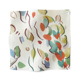 Square fabric swatch in a painterly leaf print in a rainbow of shades on a white field.