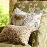 Decorative pillows with floral patterns on a green upholstered chair.