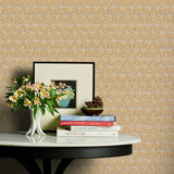 Decorative table with books and flowers against a brown and blue floral wallpaper.