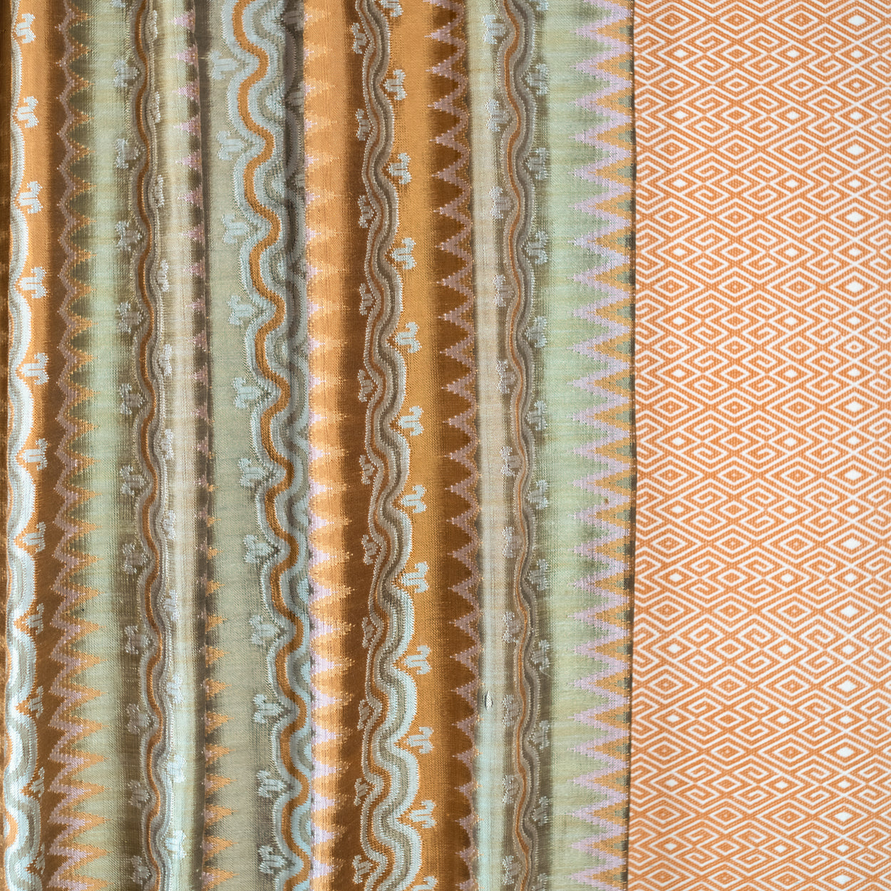 Patterned fabric with vertical stripes and geometric designs in brown, green, and beige.