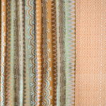 Patterned fabric with vertical stripes and geometric designs in brown, green, and beige.