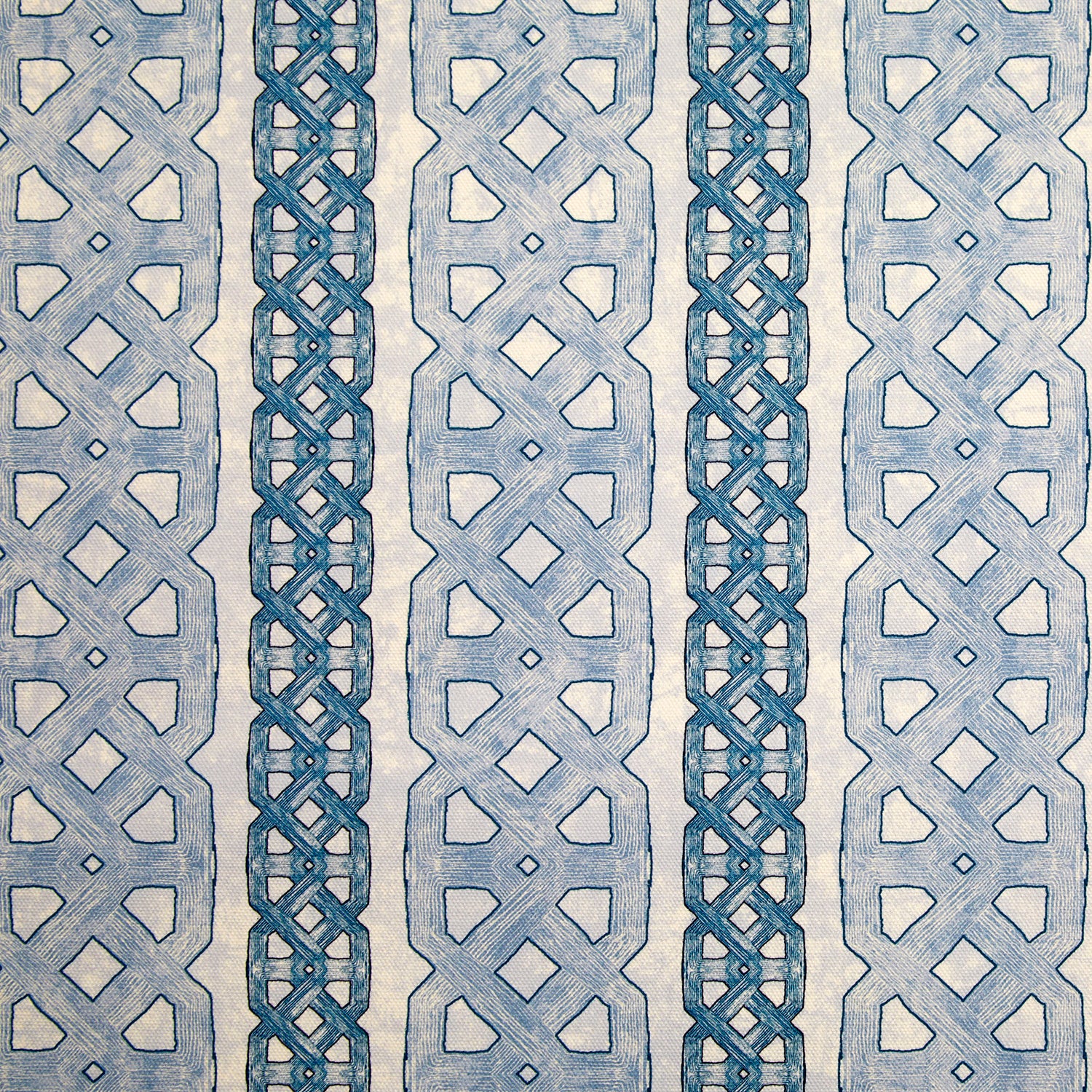 Detail of fabric in a geometric stripe print in blue and navy on a mottled tan field.