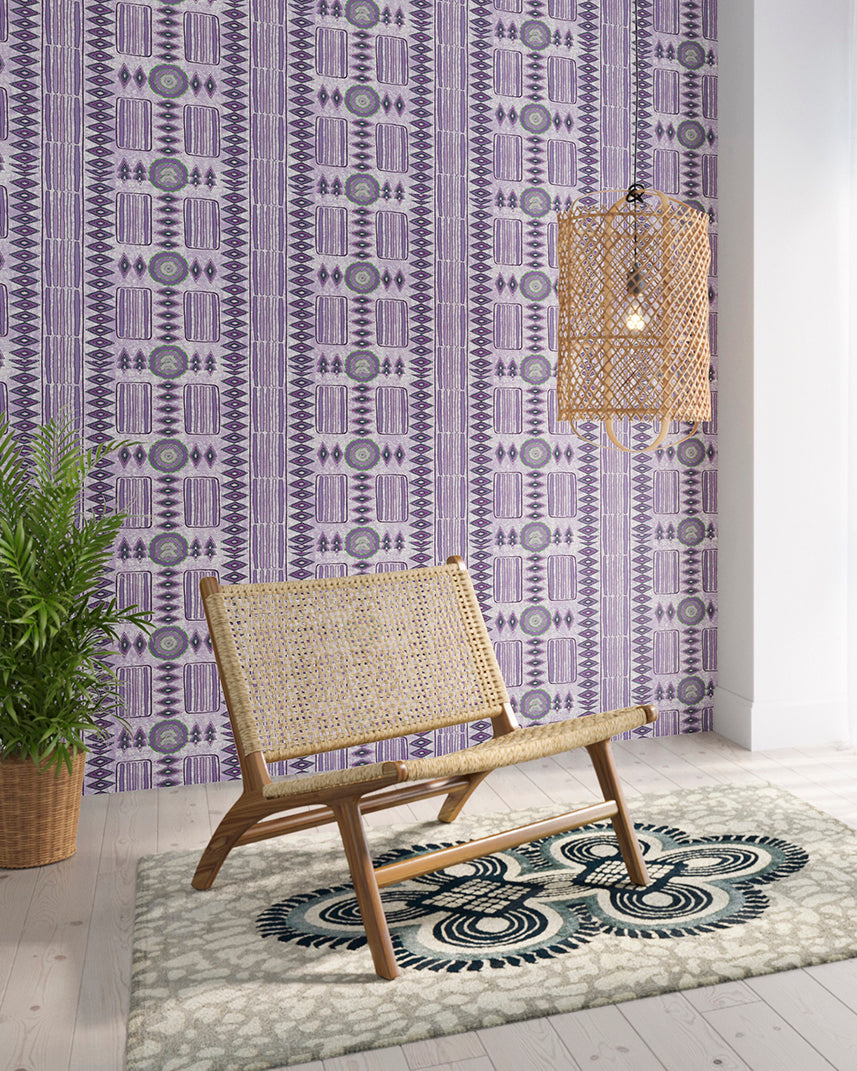 Styled living room tableau with a wall papered in a geometric stripe print in purple with green accents.