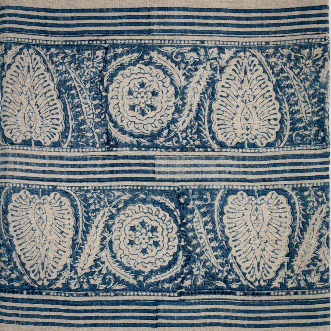 Block printed fabric in an ornamental paisley stripe in indigo on linen.