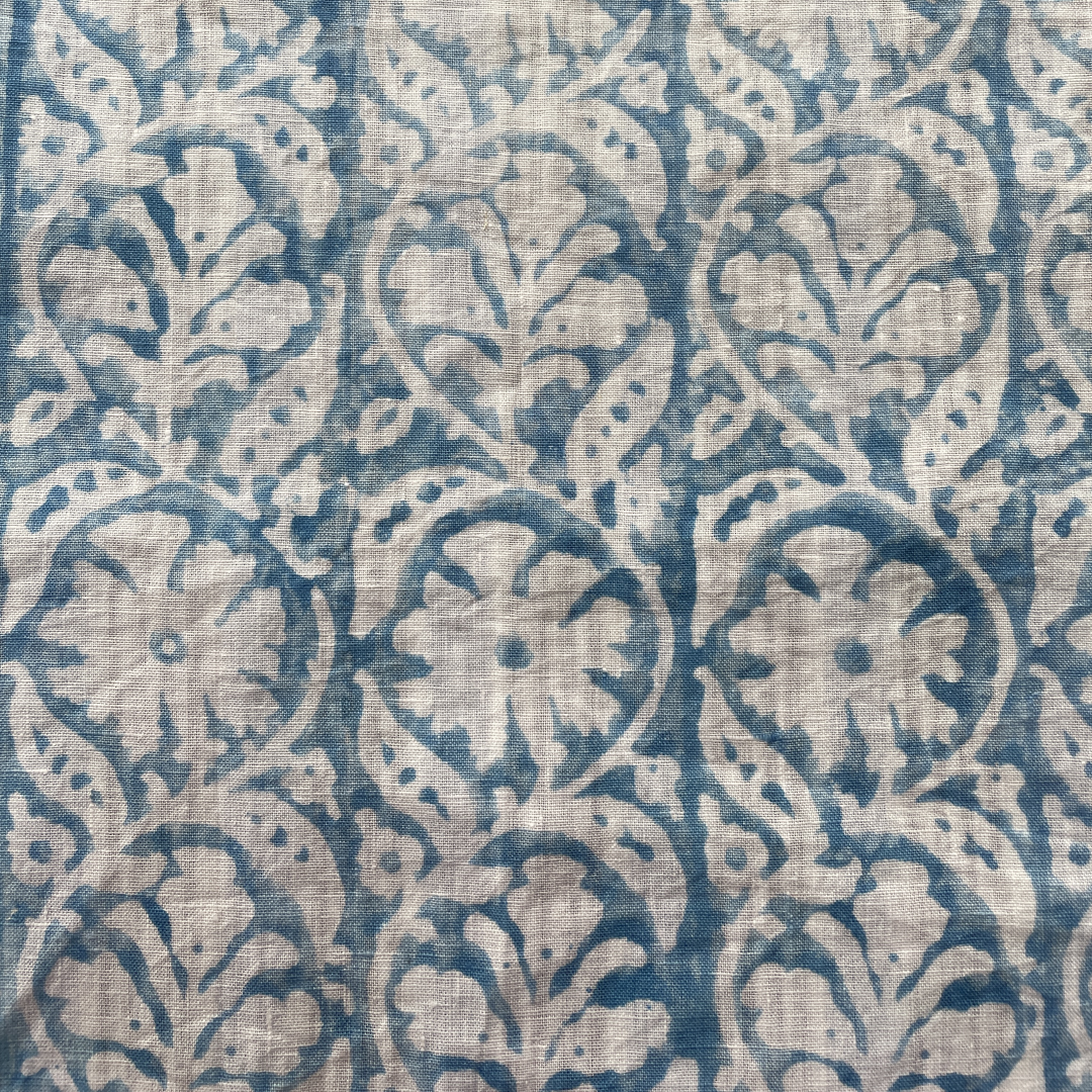 Block printed fabric in a scrolling floral stripe in blue on linen