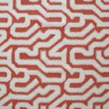 Detail of fabric in a playful meandering print in white on a coral field.