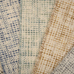 A pile of broadloom carpets in textural basket weaves in an array of colors. 