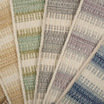 Broadloom carpet samples spread in an arc in a striped pattern in a range of colors. 