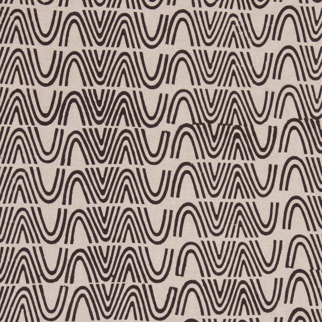 Detail of fabric in an abstract curvilinear stripe in black on a tan field.