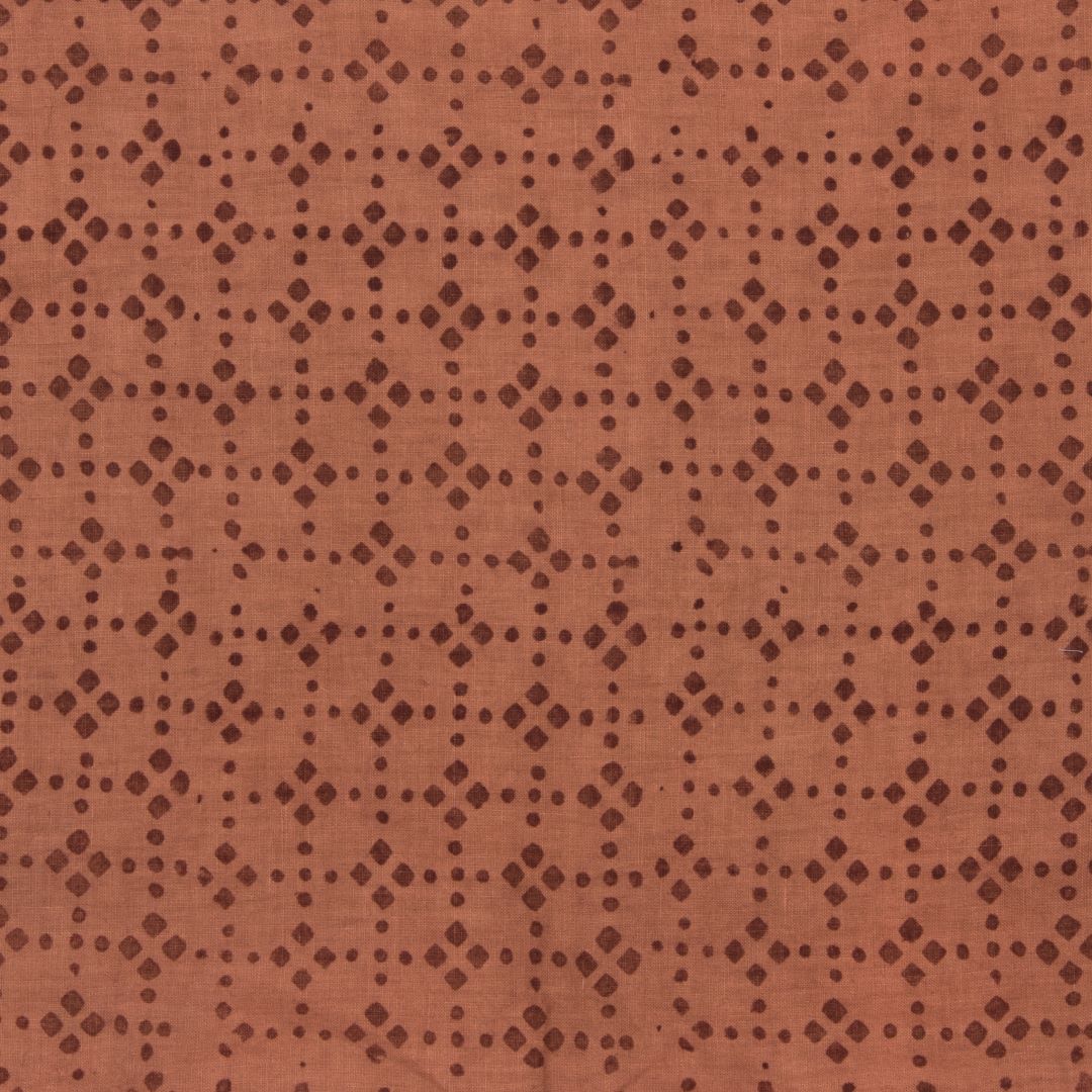 Detail of fabric in a geometric lattice print in brown on a burnt orange field.