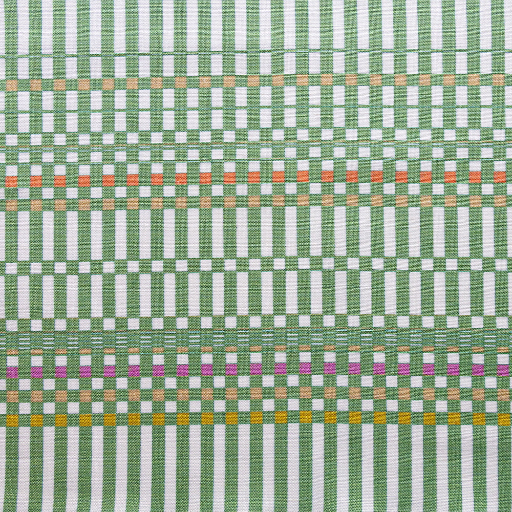 Detail of fabric in a dense irregular check print in green with red, yellow and purple accents on a white field.