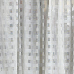 Detail of a draped sheer fabric in a check pattern in ivory.