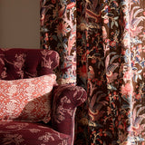 Decorative armchair with floral patterned fabric against a curtain with a botanical & bird pattern.