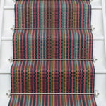 Striped flatweave runner in pink green purple blue with black border on white staircase
