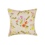 A throw pillow with a hand drawn brightly colored floral print on a light pink ground.