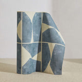 A curved partition stands on the ground, covered in a geometric grid print in blue-gray and cream.