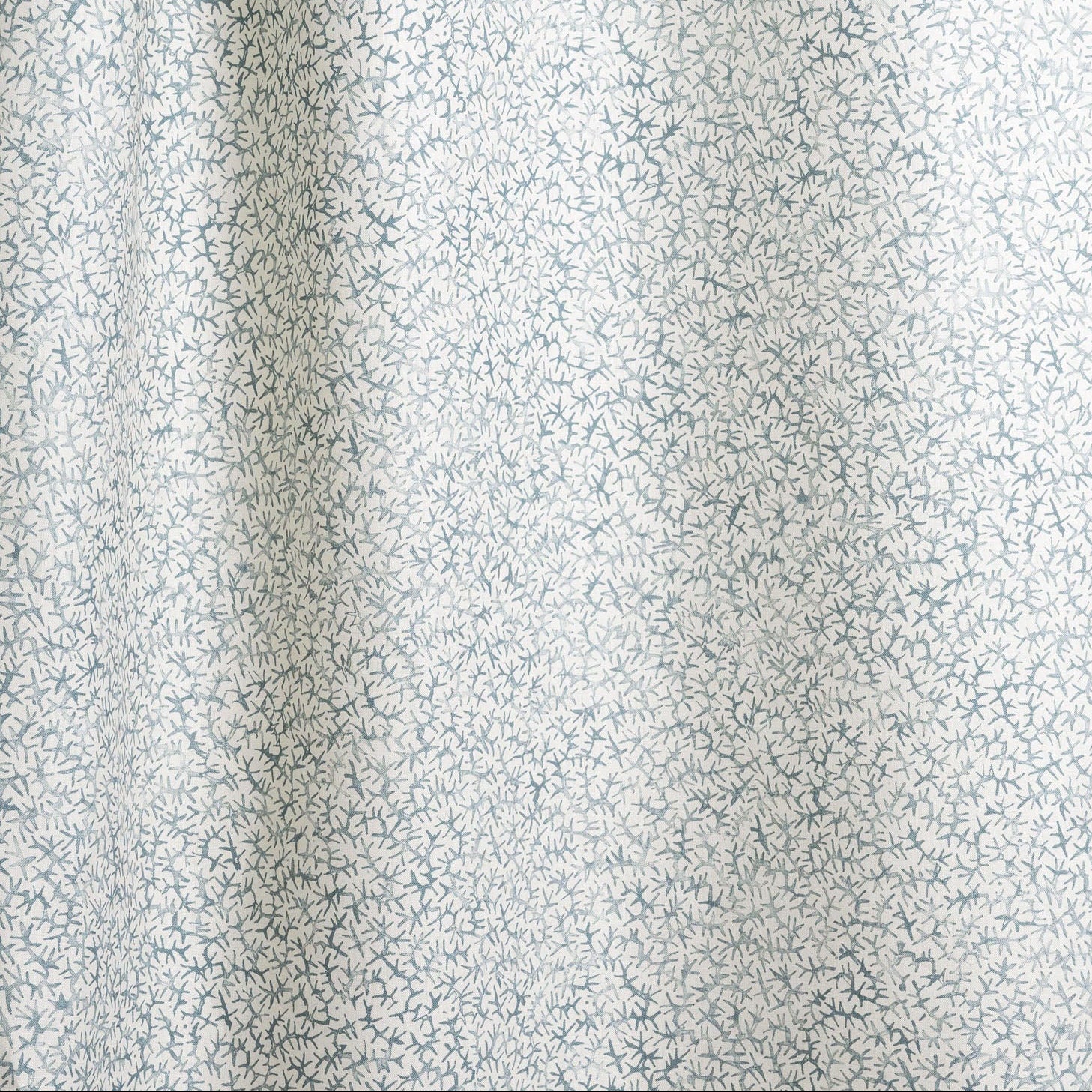 Draped fabric with small scale coral design in light blue on white. 