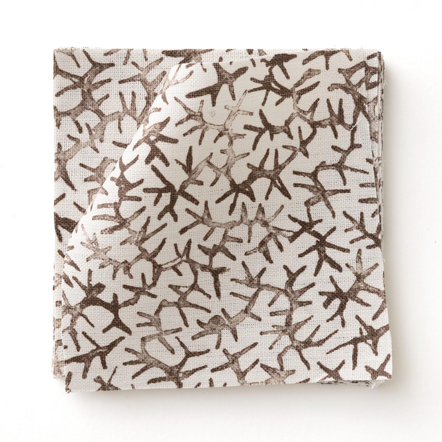 Fabric swatch with small scale coral design in dark brown on white. 