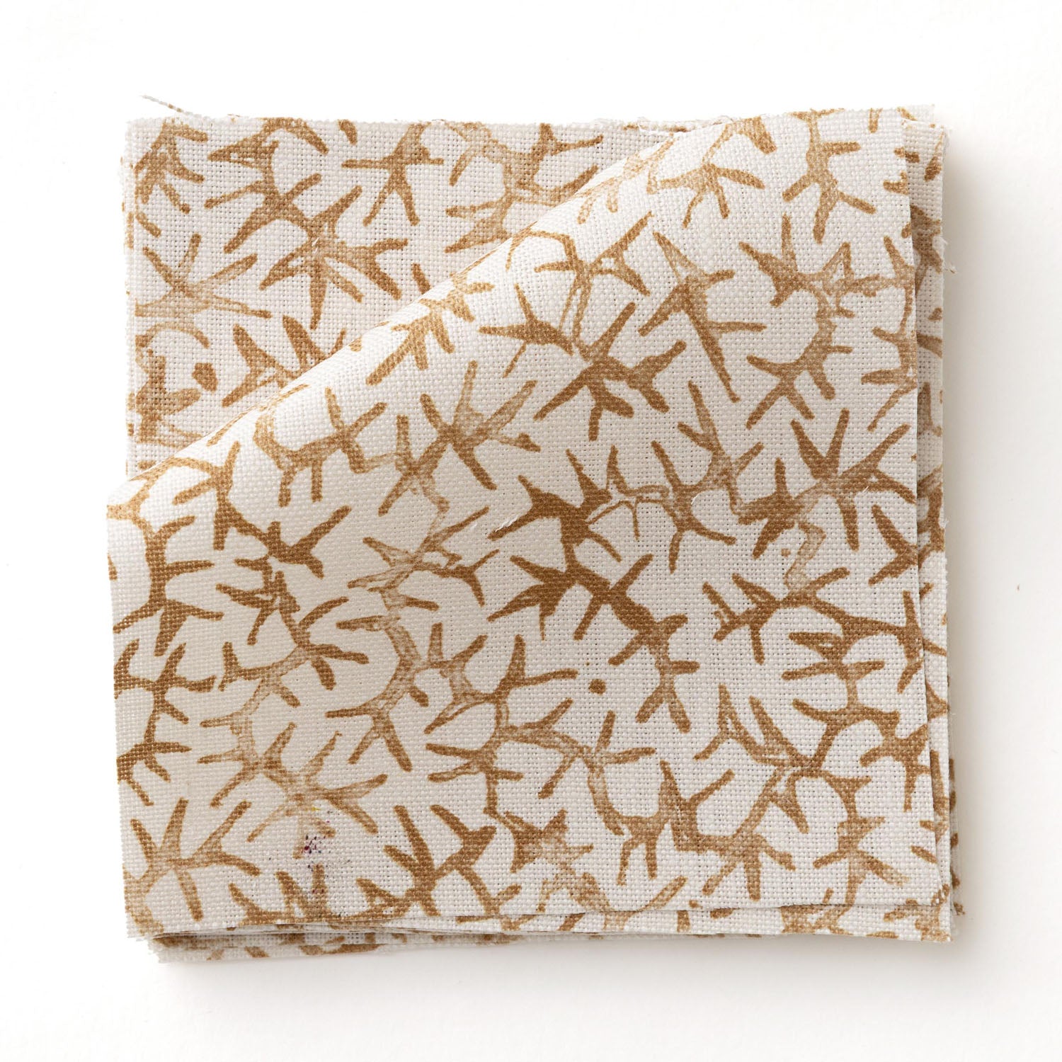 Fabric swatch with small scale coral design in warm tan on white. 